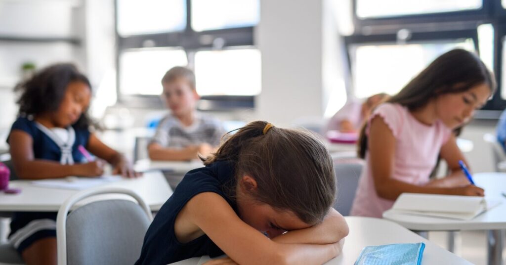 child struggling at school with head on desk; IEP, advocating for your neurodiverse child at school